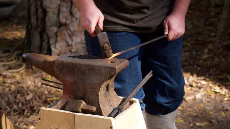 flattening a piece of metal with blacksmith hammer