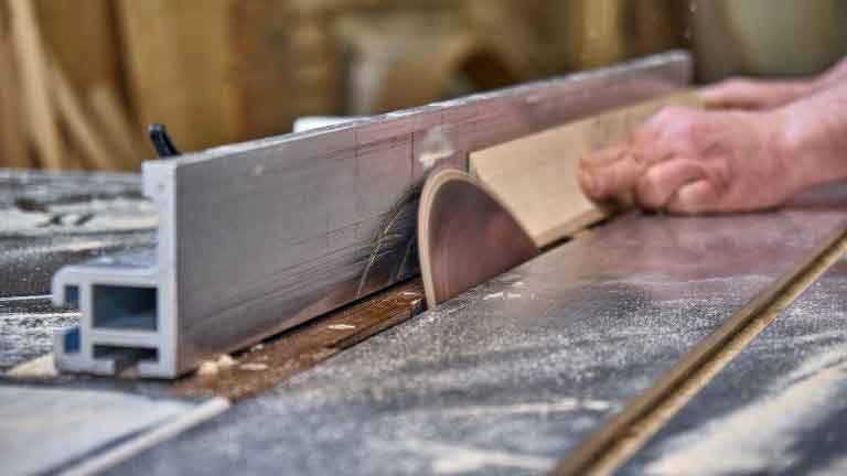 man cutting wood block with a table saw