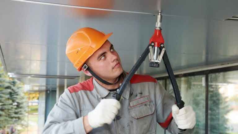 worker inserting nuts with a rivnut tool